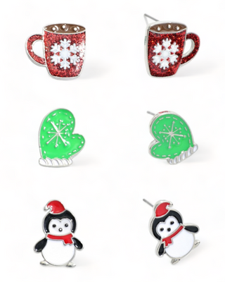 A set of holiday-themed stud earrings including red glittery mugs with snowflakes, green mittens with snowflake details, and penguins wearing Santa hats and scarves