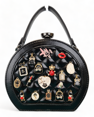 Black crossbody handbag with a quilted face and adorned with charms.