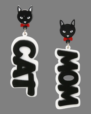 A pair of Cat Mom earrings with black cat studs featuring red bows, and bold black and white text drops reading "CAT" and "MOM".