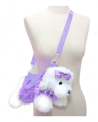  plush white dog crossbody bag with a purple glittery dress and a matching purple bow on its head. The bag has a purple adjustable strap and is showcased on a mannequin