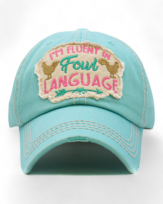 A distressed turquoise baseball cap featuring an embroidered patch with the text "I'm Fluent in Fowl Language" and chicken graphics, perfect for adding a touch of humor to your outfit.