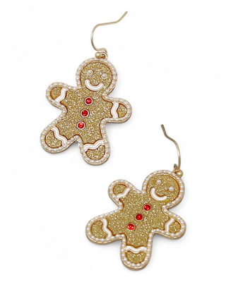 A pair of glittering gingerbread man dangle earrings, featuring gold sparkle, red button accents, and white pearl-like icing details.