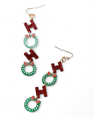 Long dangle earrings featuring red glitter "Ho Ho Ho" letters with green wreaths adorned with small red bows.