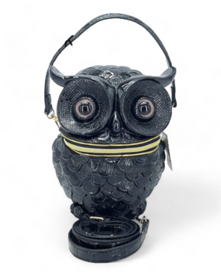 A black owl-shaped handbag with intricate feather detailing and large eyes, including a detachable shoulder strap