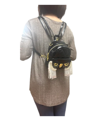 Model wearing black owl shaped backpack with shiny décor