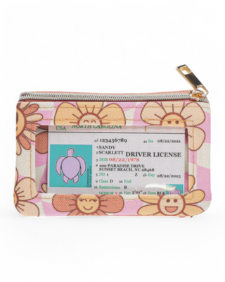 A small zippered wallet with a clear ID window, featuring a cheerful floral print on a checkered background with gold-tone hardware.