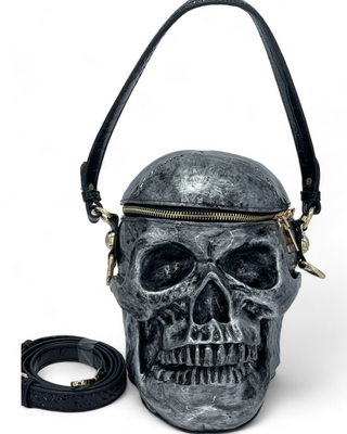 Skull-shaped crossbody handbag with a textured silver metallic finish, featuring a zippered top and detachable strap