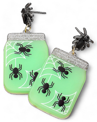 Glow-in-the-dark earrings featuring a jar design with spiders and webs, topped with a glittery lid and black spider stud attachments.