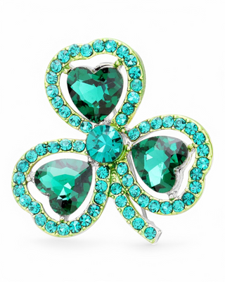 A St. Patrick’s Day shamrock brooch adorned with sparkling green gemstones in a heart-shaped clover design, set in a silver-tone frame with a secure pin-back closure.