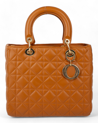 A brown quilted handbag with rounded handles, accented by gold-toned metal rings and a circular charm.