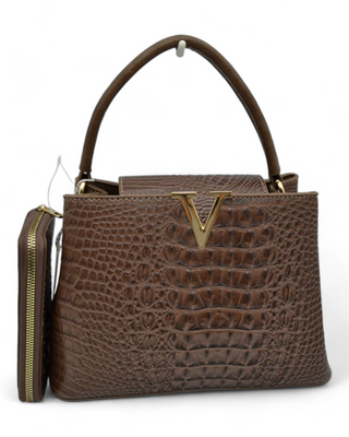 A textured handbag with a gold "V" detail on the front, featuring a top handle and an optional shoulder strap. The bag comes with a matching wallet and has a sleek, structured design.