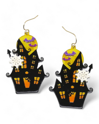 A pair of earrings designed as haunted houses with orange windows, accented by floating white ghosts and purple bats